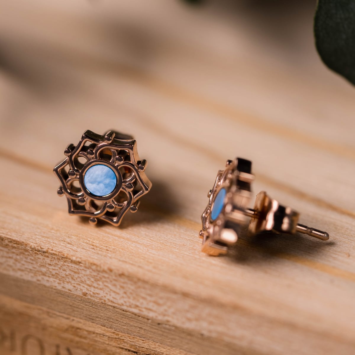 "Composition oorbellen" oorbellen in blauw nacre en rose goud, die een ingewikkelde en elegante ontwerp op een houten oppervlak.