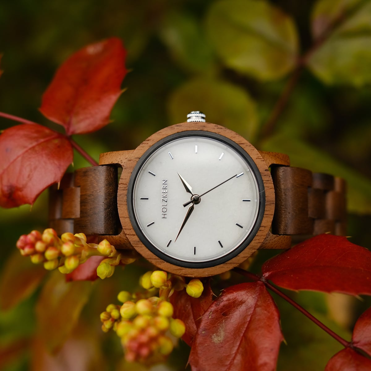 Montre Air, avec un design en bois de noyer et en marbre, élégamment placée sur un fond de feuilles d'automne vibrant.