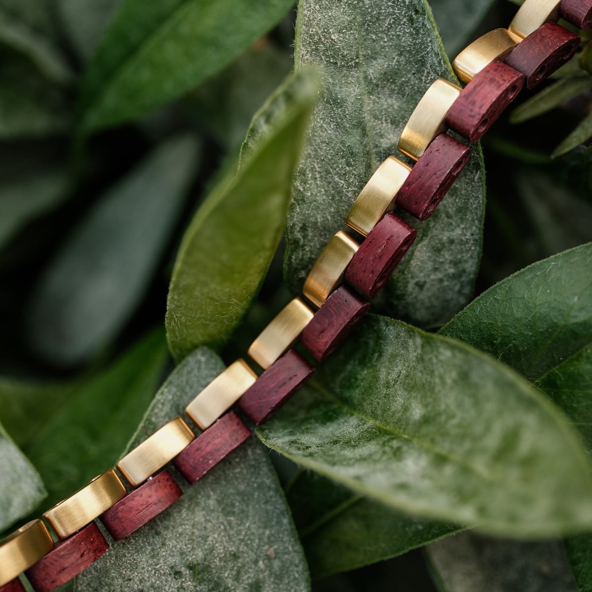 "Duet", bracelet élégant en amaranth et or, met en valeur un design géométrique sophistiqué sur fond feutré.