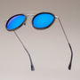 "The Enchanting" sunglasses featuring a modern design with leadwood and antique silver accents, highlighted by vibrant blue lenses.