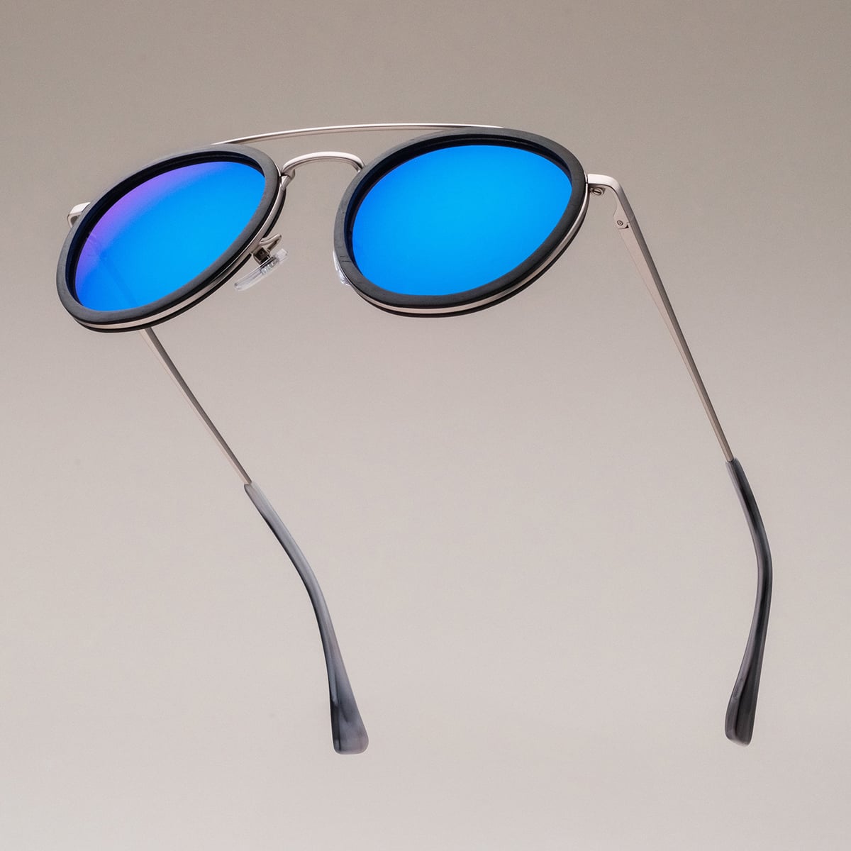 "The Enchanting" sunglasses featuring a modern design with leadwood and antique silver accents, highlighted by vibrant blue lenses.