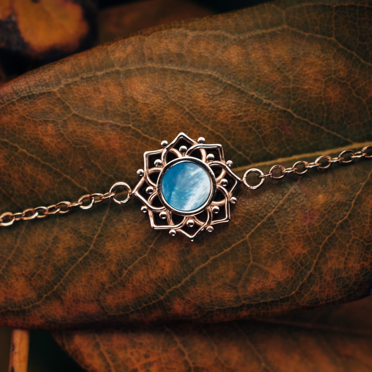 "Composition Bracelet", a bracelet with blue nacre and rose gold accents, featuring elegant, intricate design elements.