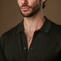 "Campania Necklace" necklace featuring a sleek walnut and Damascus style, worn by a person in a dark collared shirt.