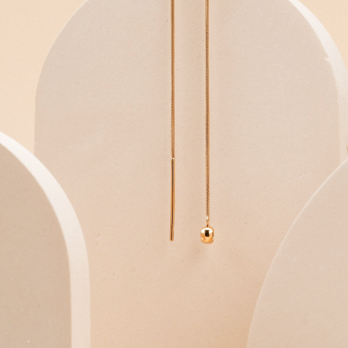 "Charms Necklace", gold charms necklace with sleek, minimalist design against a neutral backdrop.