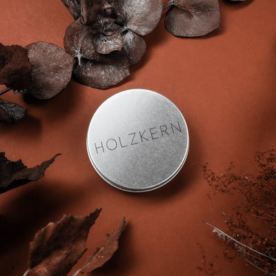 "Wood Care Balm 60ml", a wood care balm in a sleek container, set against a warm, earthy background with dried leaves.