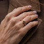 "Awakening Ring", un anillo de oro con una incrustación de mármol, usado en una mano para un estilo elegante.