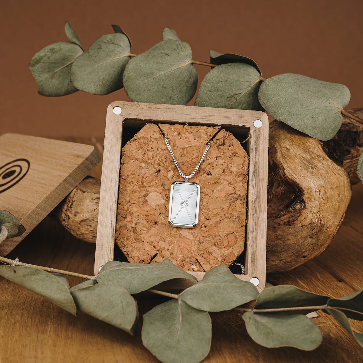 "Aquarell Collar", un elegante collar con un diseño de nácar blanco y plata, presentado en un entorno de visualización rústica.