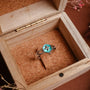 "Anillo de plata", un anillo de plata con un incrustado de nacre, mostrado en una caja de madera rústica.