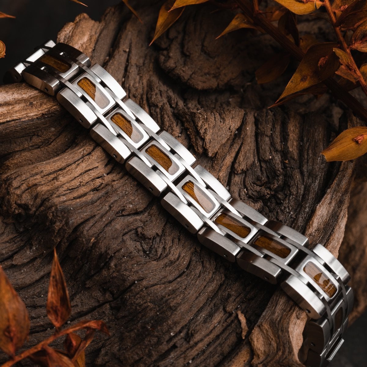 "Tremolo" bracelet, featuring a sleek walnut and silver design on a rustic wooden background.