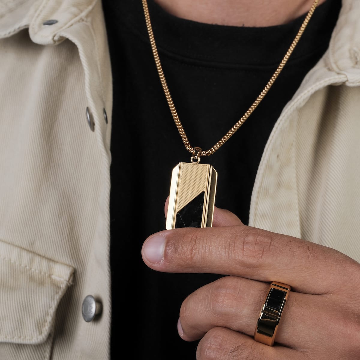 "Ionic Collier", un collier élégant avec des accents en marbre et en or, héros par une personne portant une bague dorée.