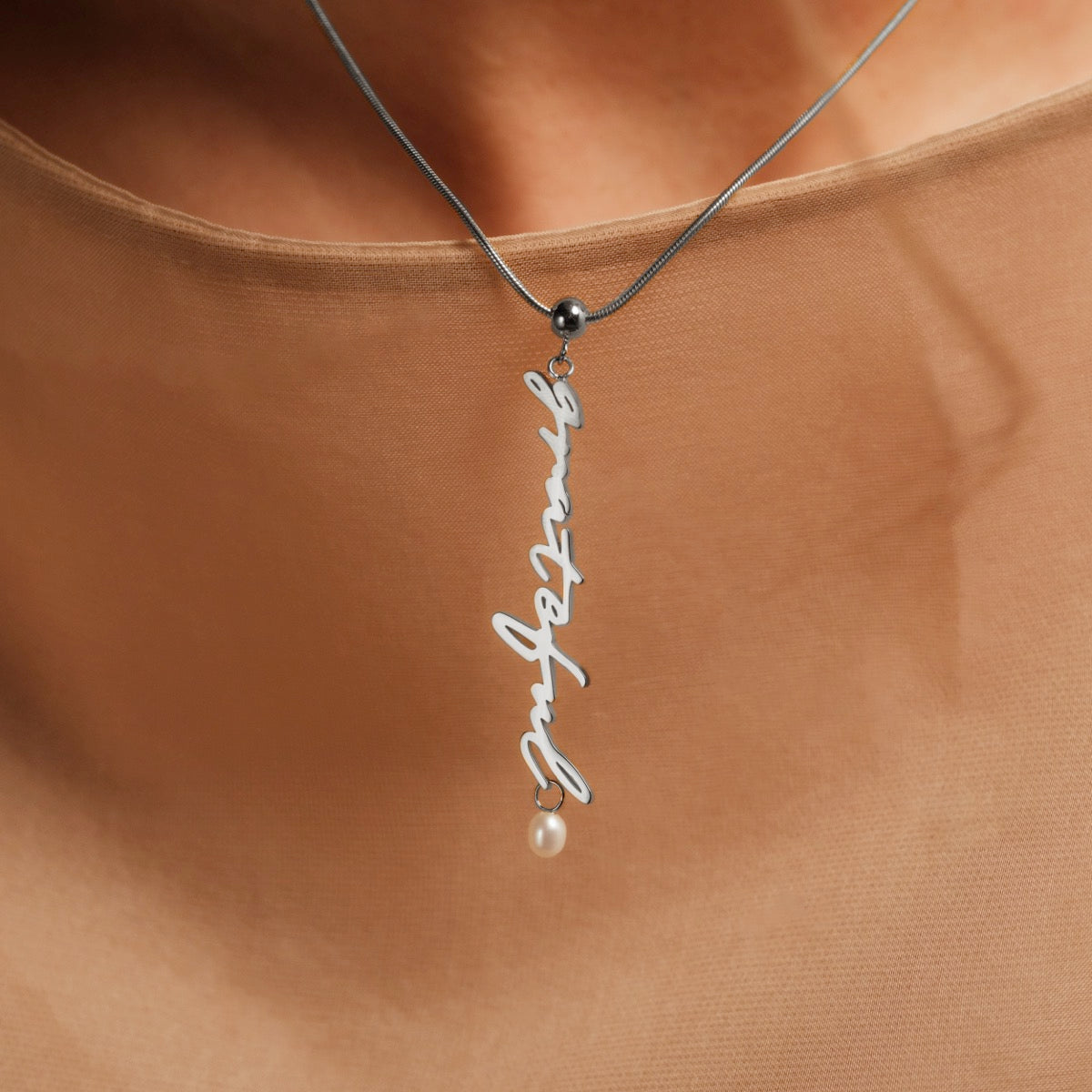 "Gratinal-Charm", elegant halskæde med en sølv charme og perle accent, fremvise en slank, minimalistisk design.