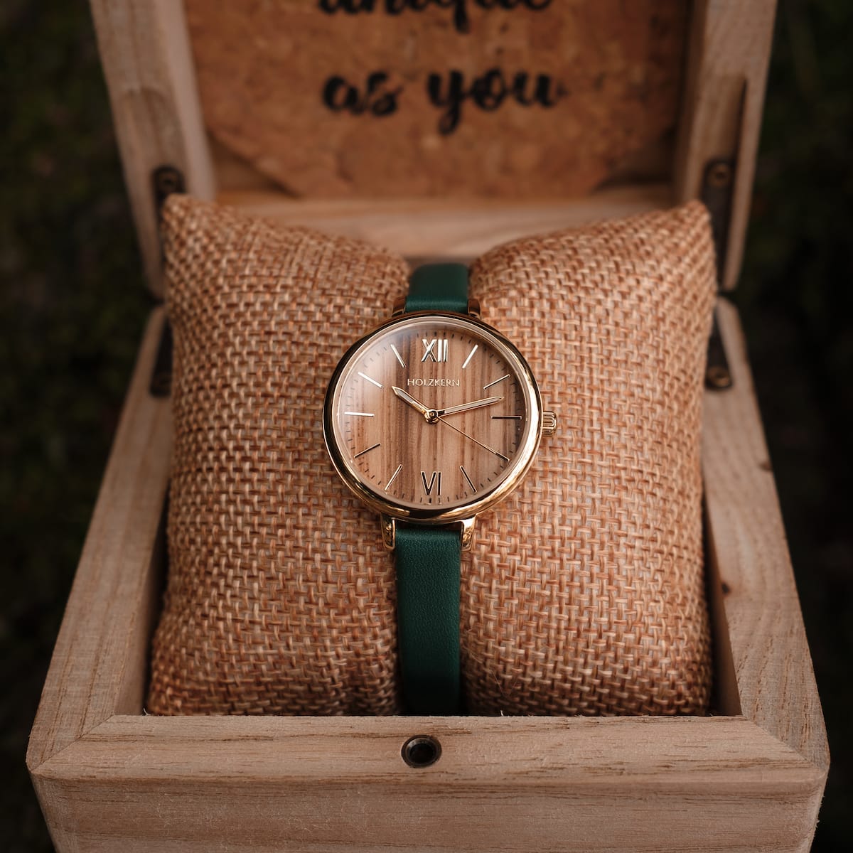 Montre "Wangari" avec visage en zèbre, accents en or et bracelet vert, dans une élégante boîte à affichage.