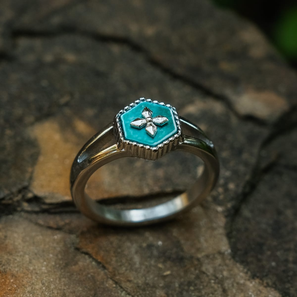"Aro Espectral", un anillo de plata y nacre que muestra un diseño floral turquesa en una banda texturada.