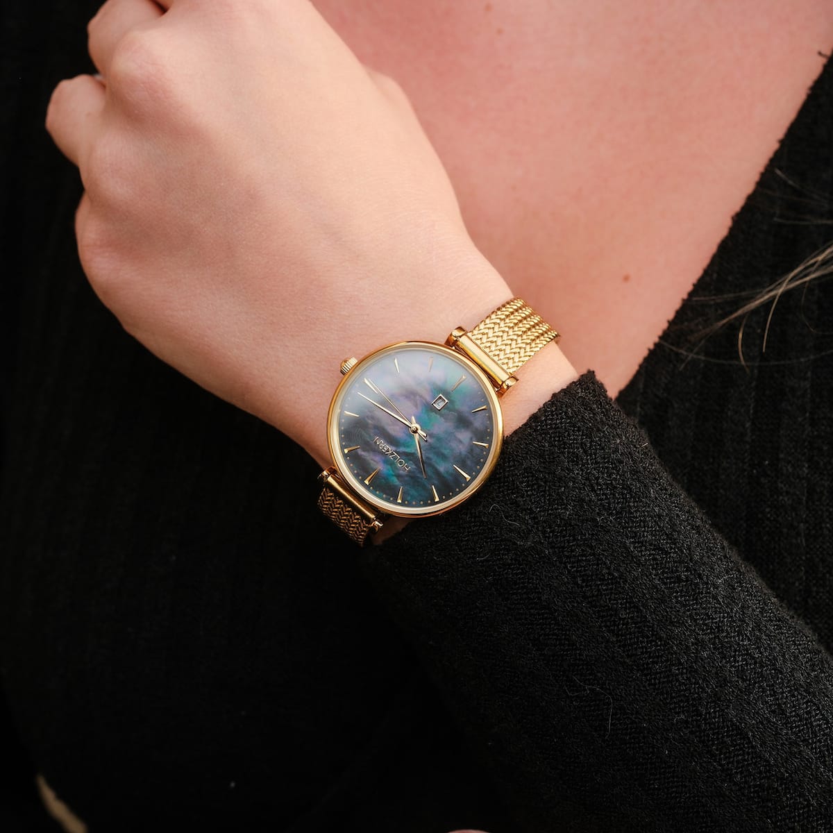 "Gigbles", une montre élégante avec un cadran nacre et un bracelet en maille dorée, porté sur un poignet.
