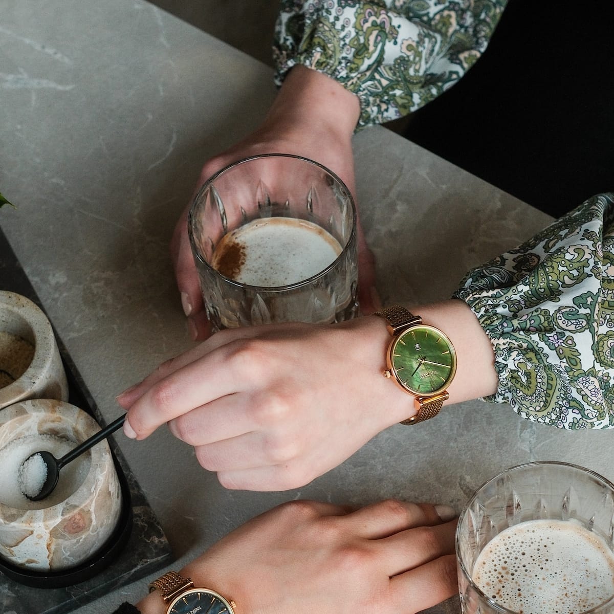 "Sunnyside" ur med en nacre og guld design, stilfuldt slidt i et afslappet kaffeøjeblik.