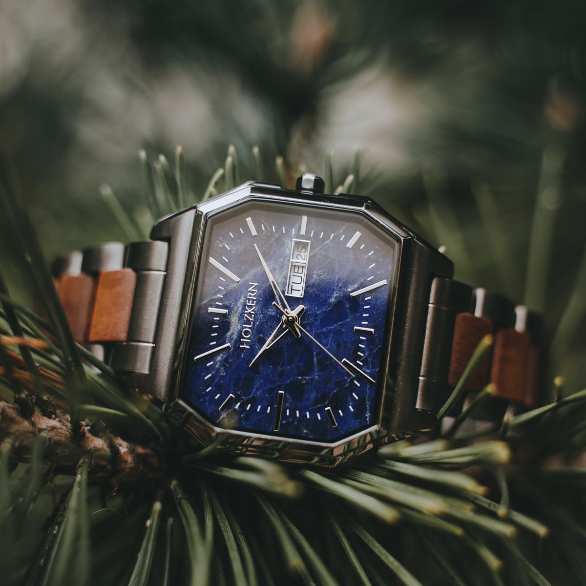 "Moneo" reloj con koa y mármol con acentos de plata en un fondo de la naturaleza.