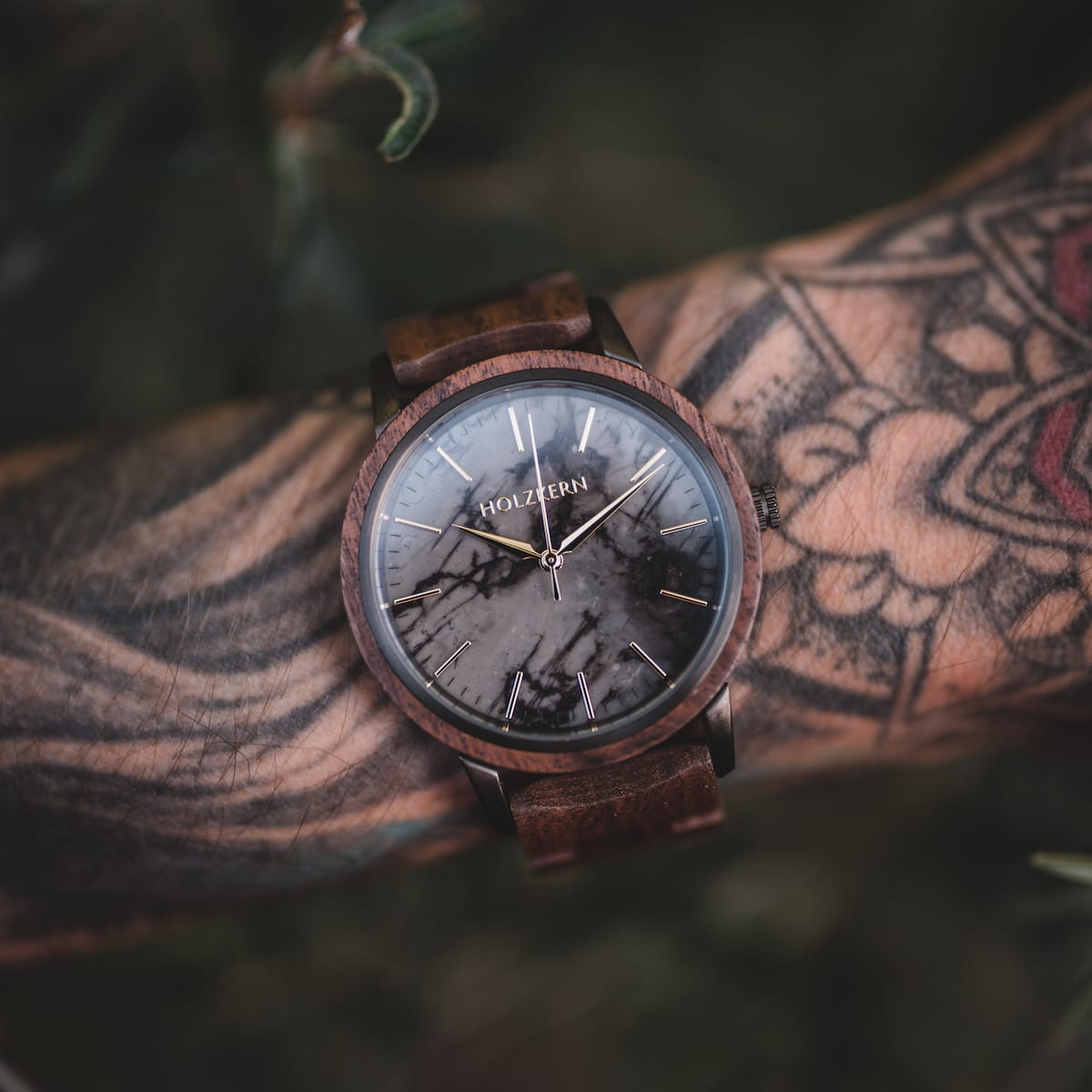 "Leonardo" watch featuring a walnut and marble design on a tattooed wrist, highlighting its rustic elegance.