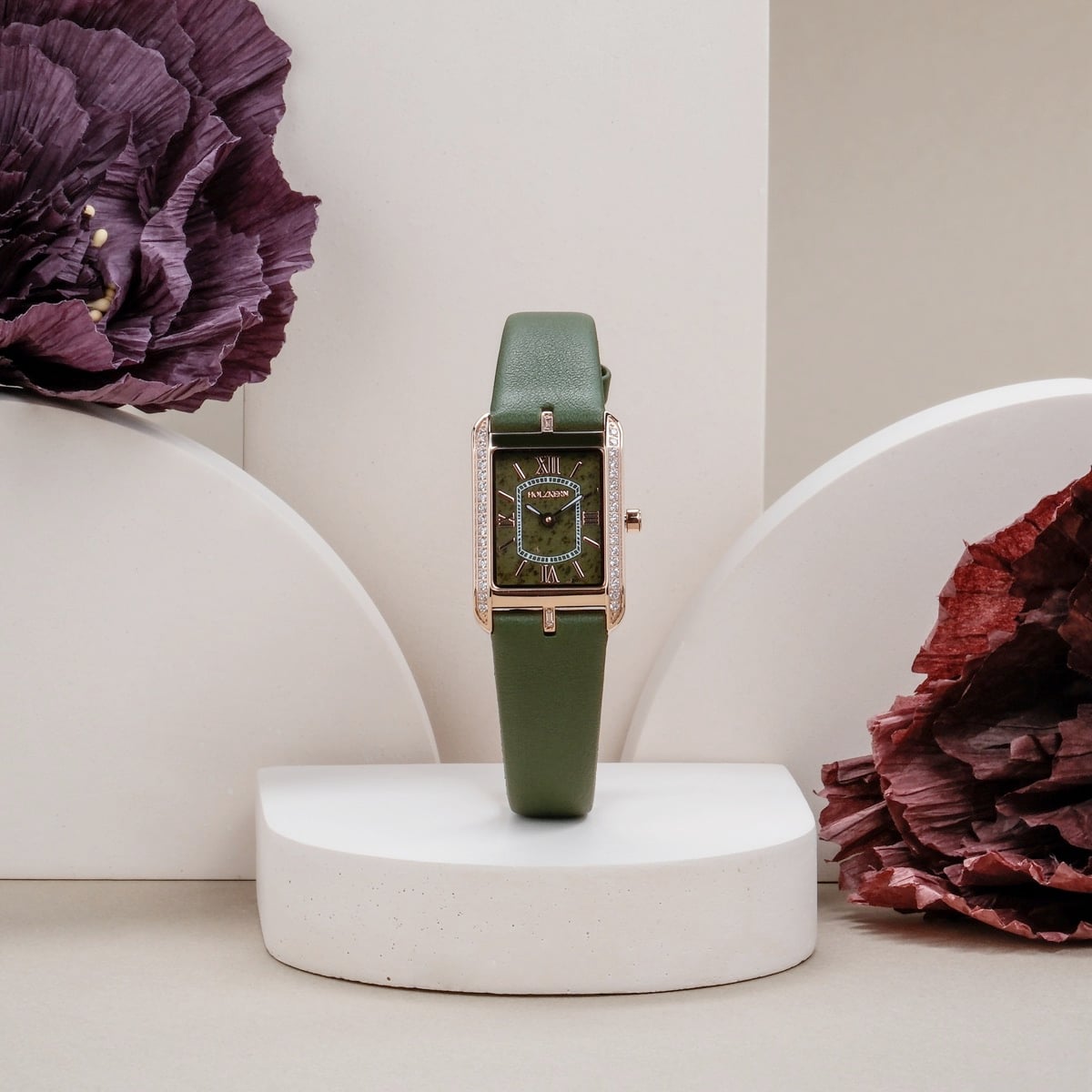"Memoire", elegant green watch with a rectangular face and floral accents, set against a minimalist backdrop.