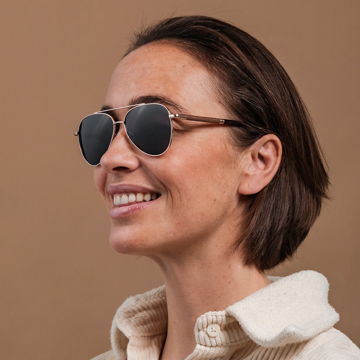 Les lunettes de soleil "The Badass I" en noyer et en or mat, au design épuré et moderne.